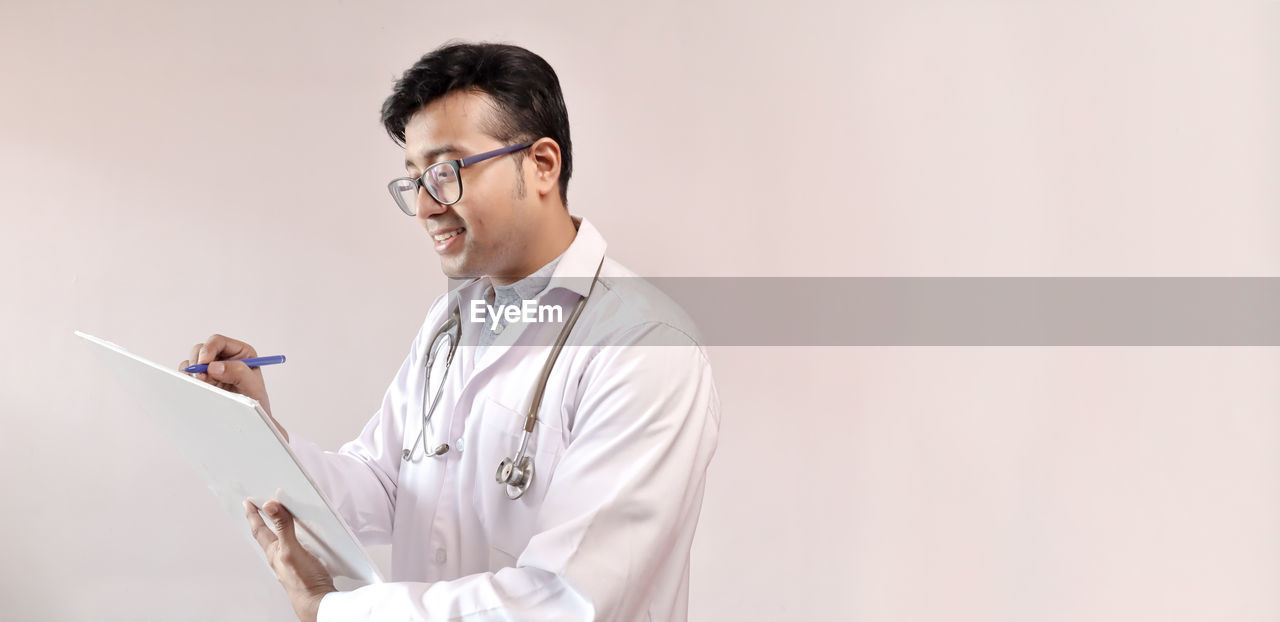 Doctor writing in paper against white background