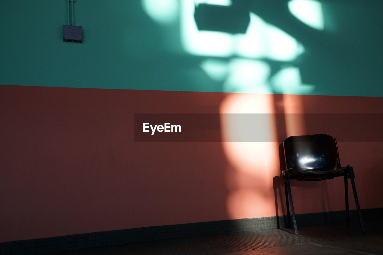 Empty chairs on table against wall