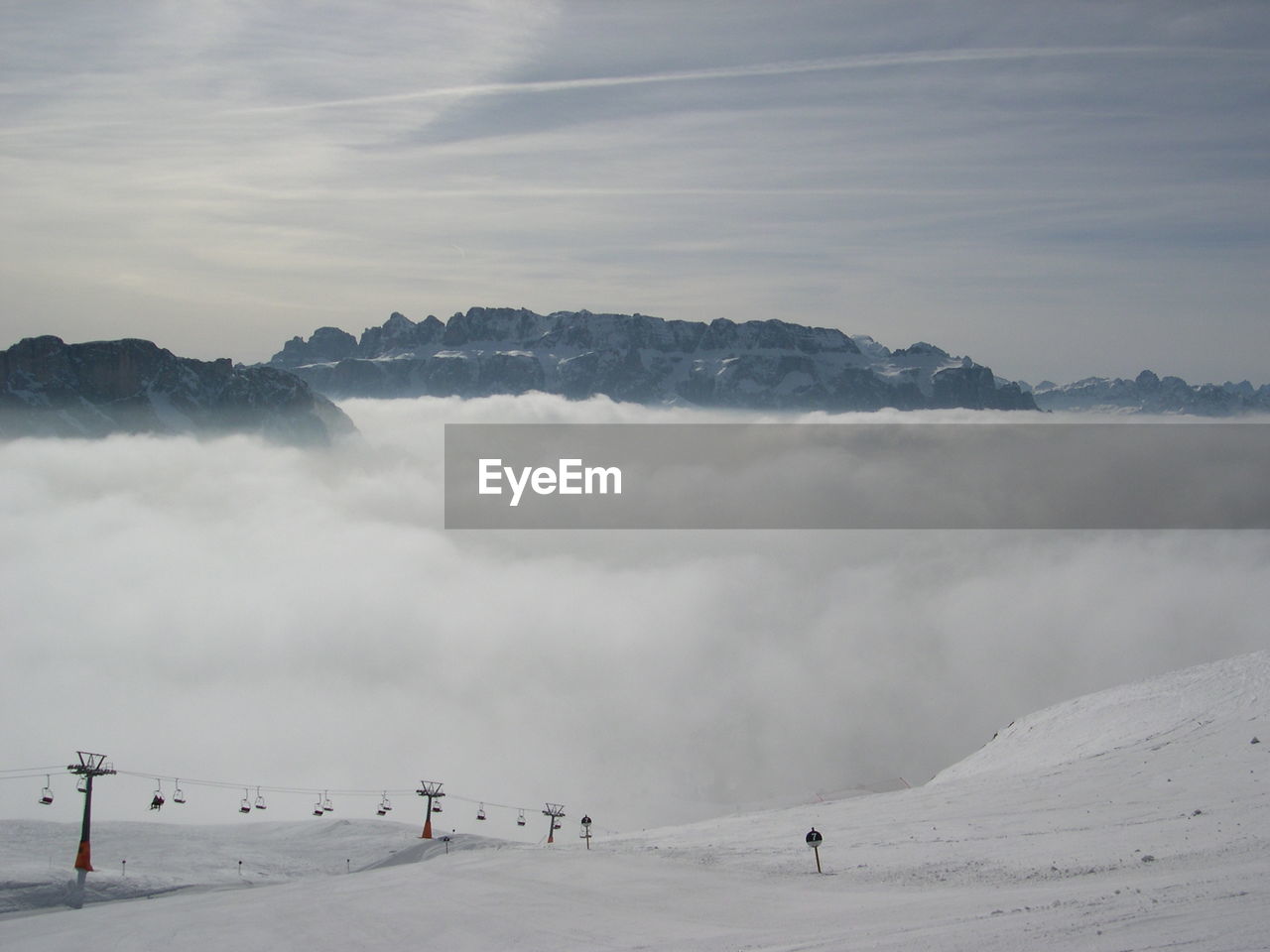 Snowy landscape against clouds covered mountains