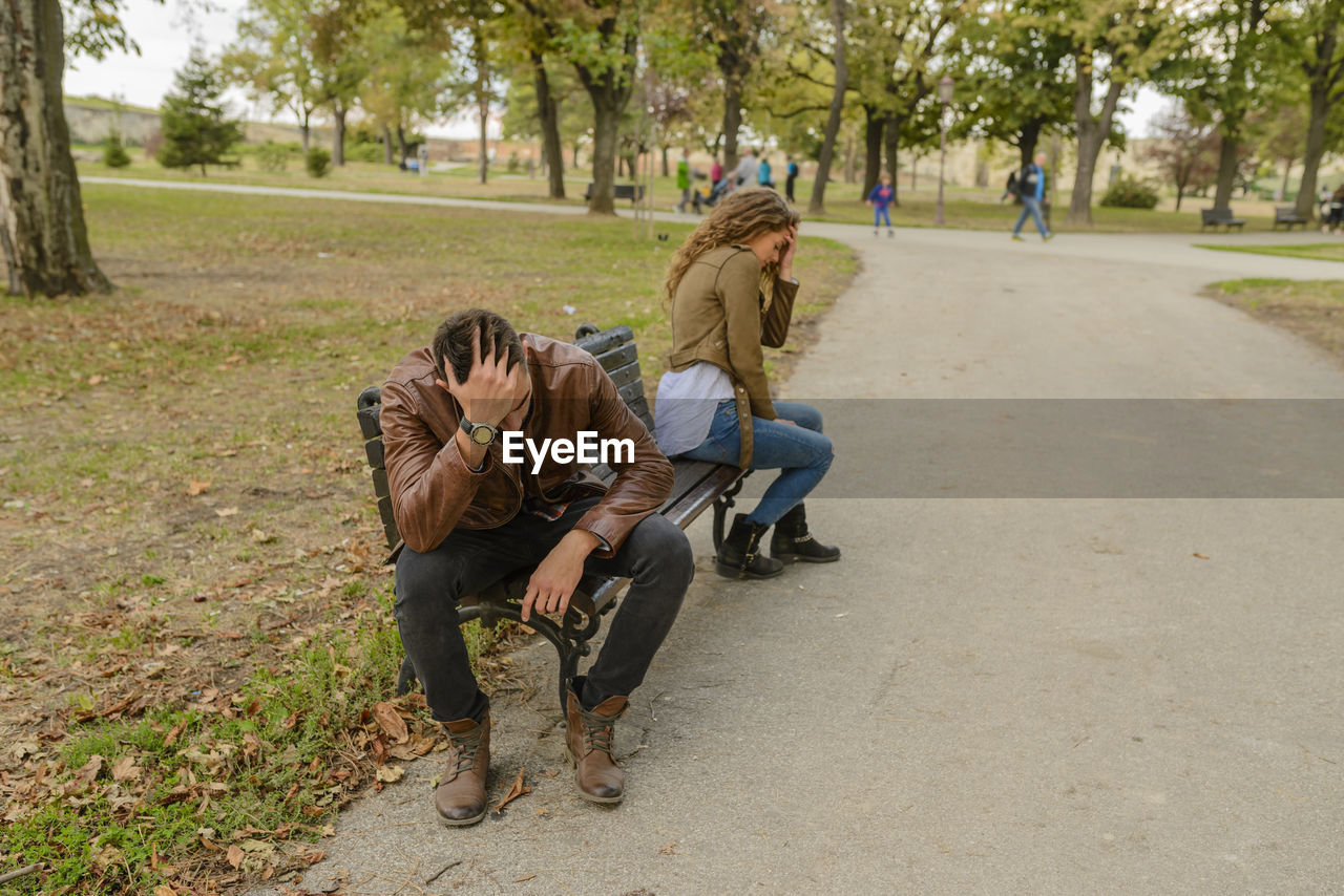 Angry couple sitting on bench at park