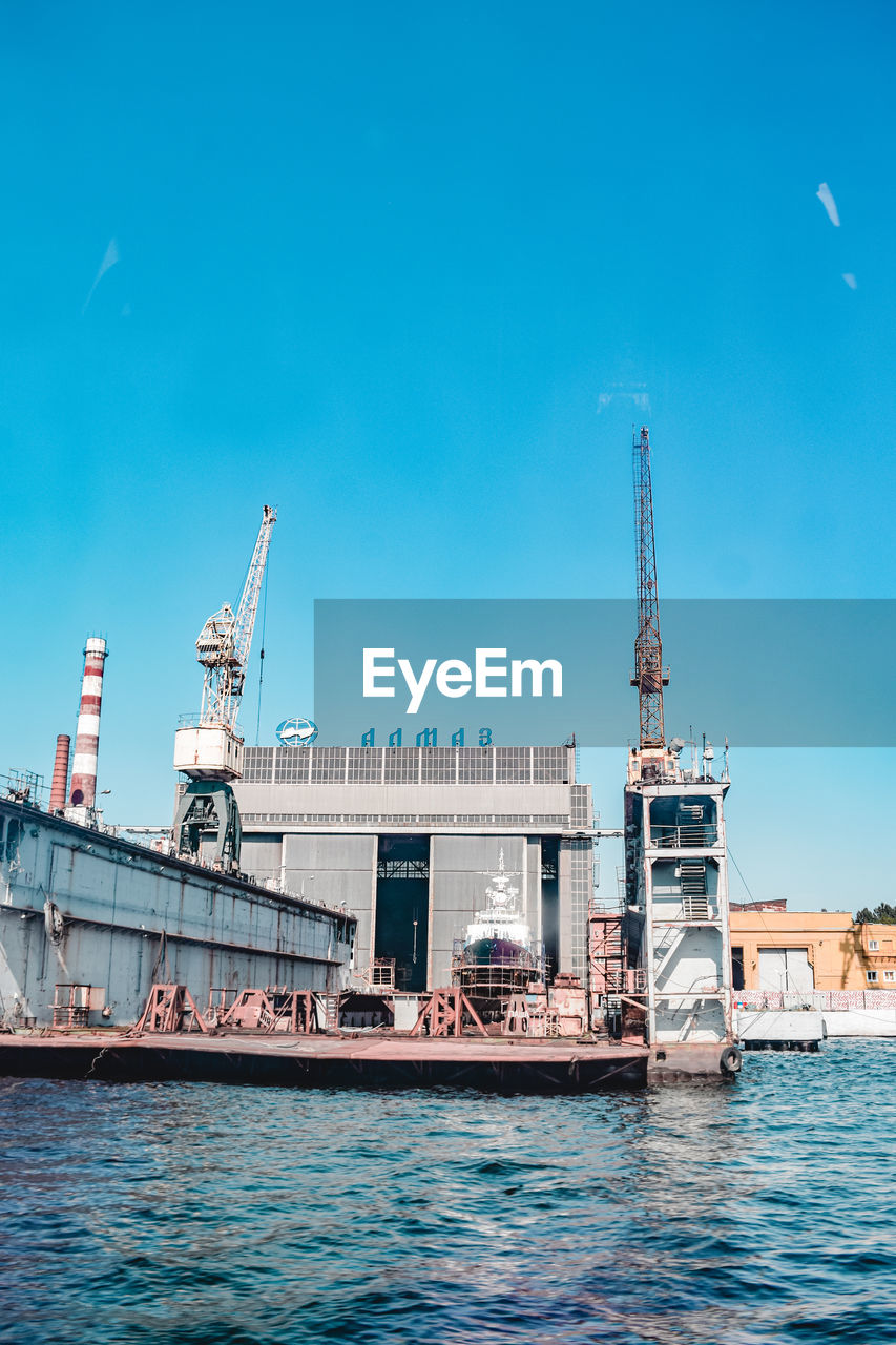 CRANES AT COMMERCIAL DOCK AGAINST BLUE SKY