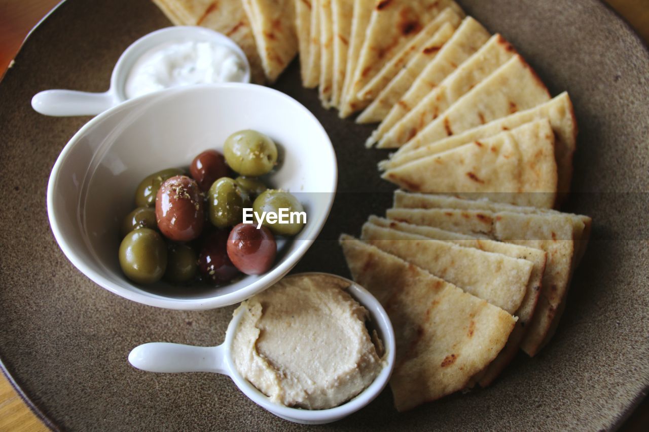 High angle view of olives and humus in bowl on table