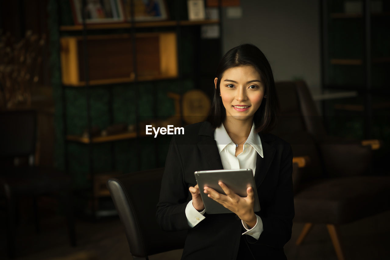 Portrait of smiling young businesswoman using digital tablet in office
