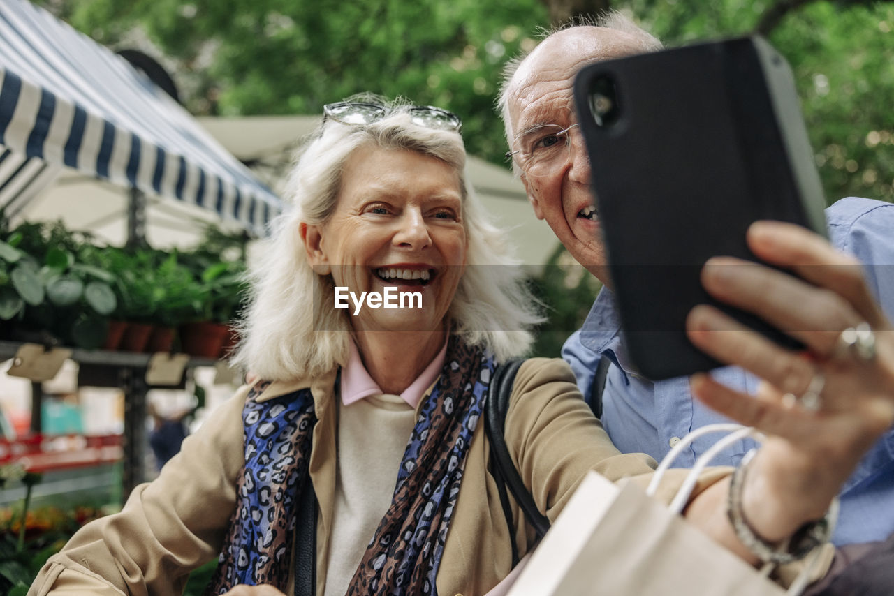 Happy senior woman taking selfie with man through smart phone