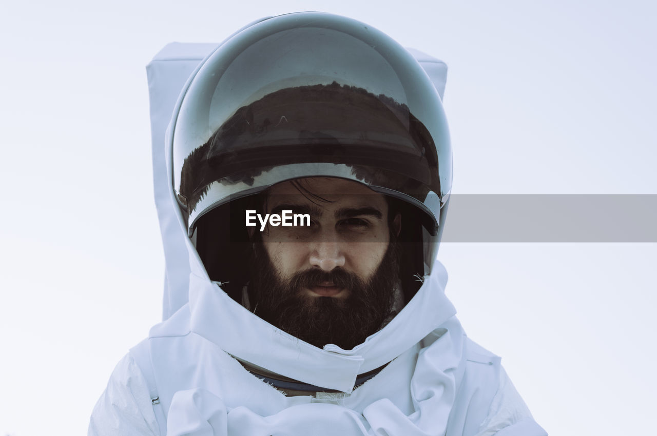 Portrait of young man in astronaut costume against white background