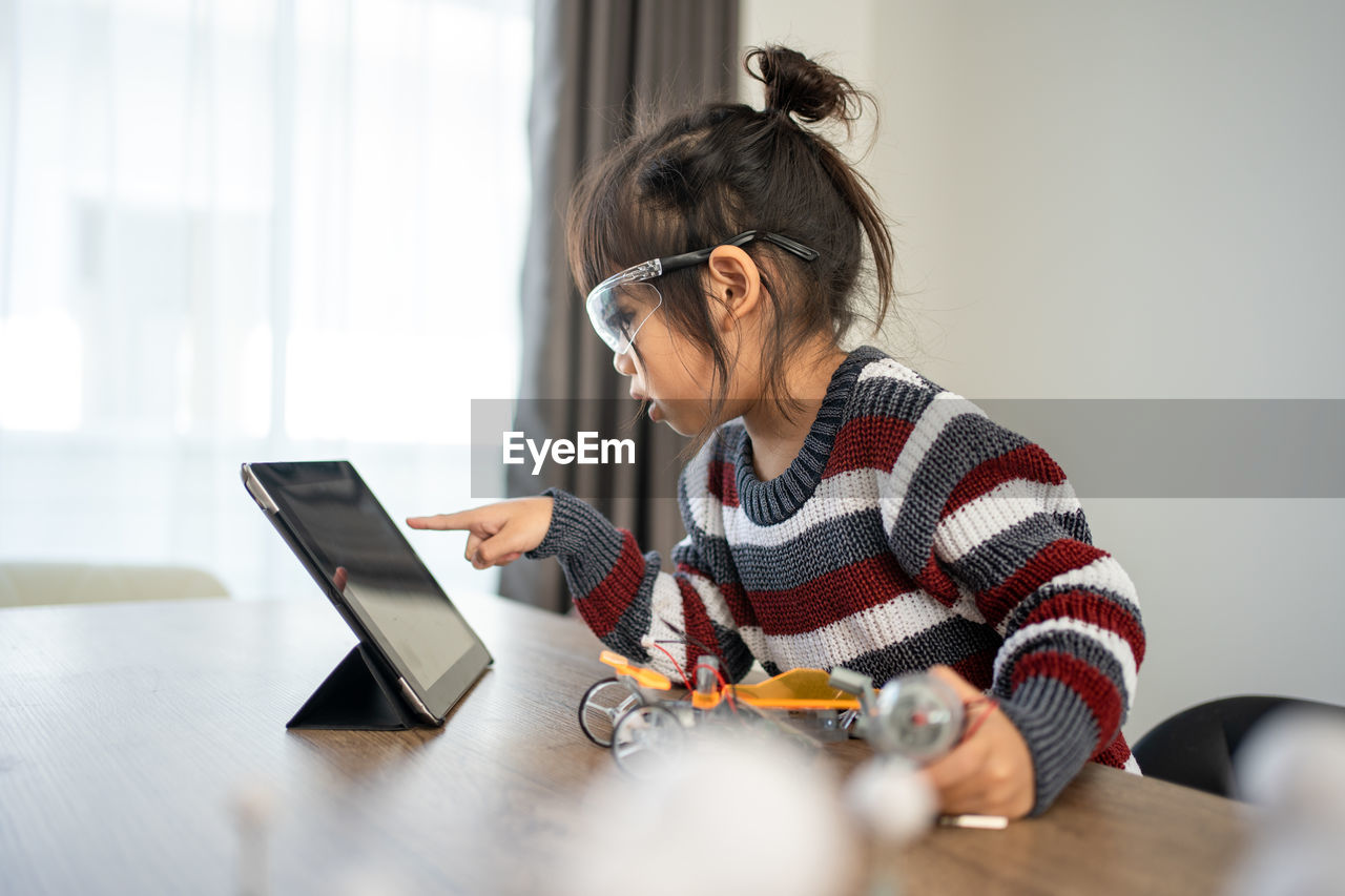 Cute girl looking at digital tablet during online classes