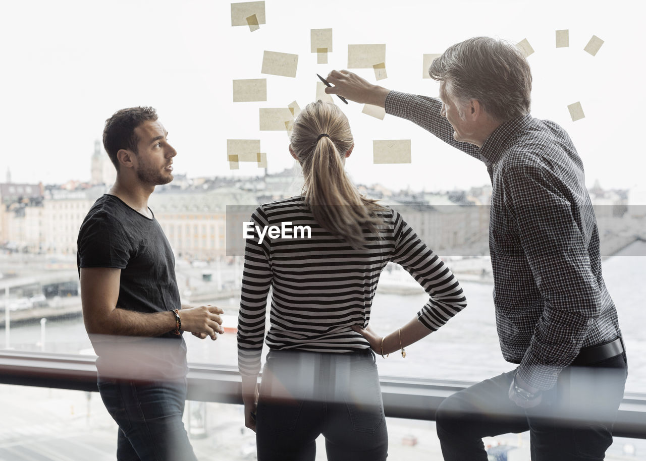 Businessman explaining adhesive notes to colleagues in office
