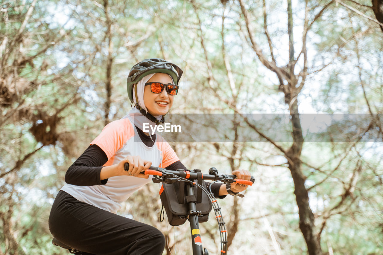 Smiling young woman on bicycle at park