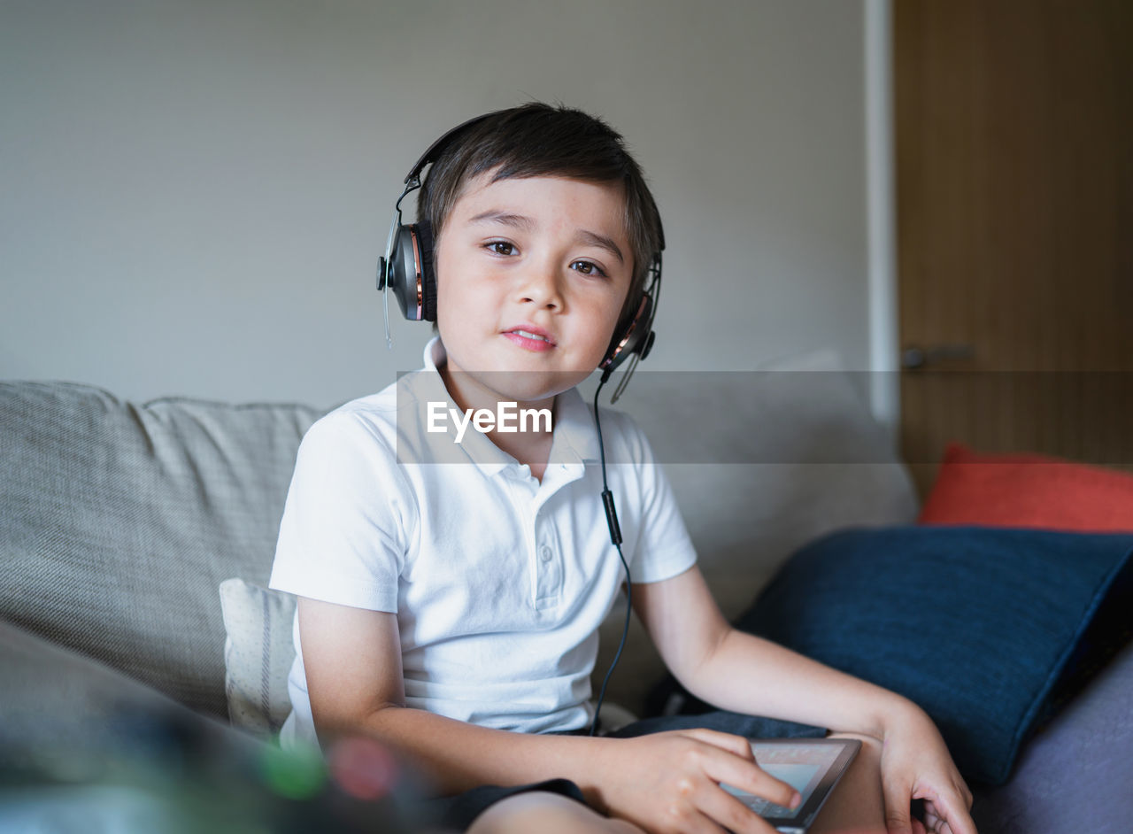 Kid wearing headphone listening to music,child boy doing homework by using digital tablet