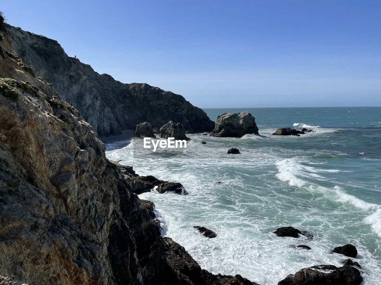 ROCKS ON BEACH AGAINST CLEAR SKY