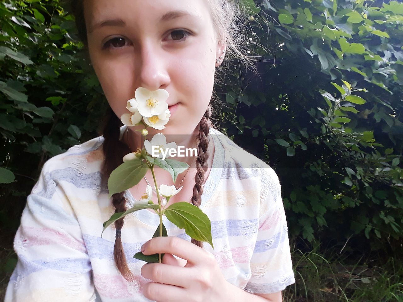 CLOSE-UP OF YOUNG WOMAN WITH FLOWERS IN PARK