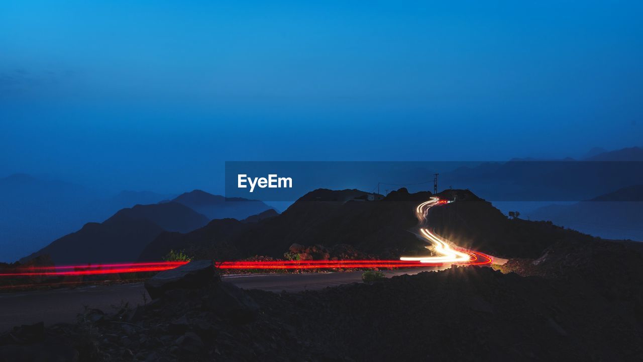 Light trails on mountain against sky at night