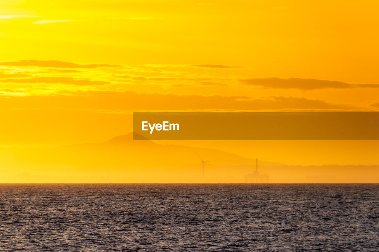 Wind turbine and oil rig at sunset, fife coast, firth of forth, scotland