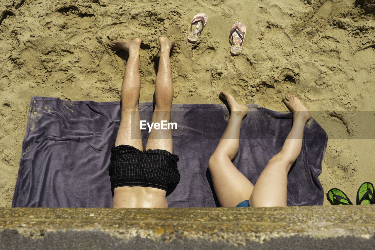 LOW SECTION OF PEOPLE RELAXING ON BEACH