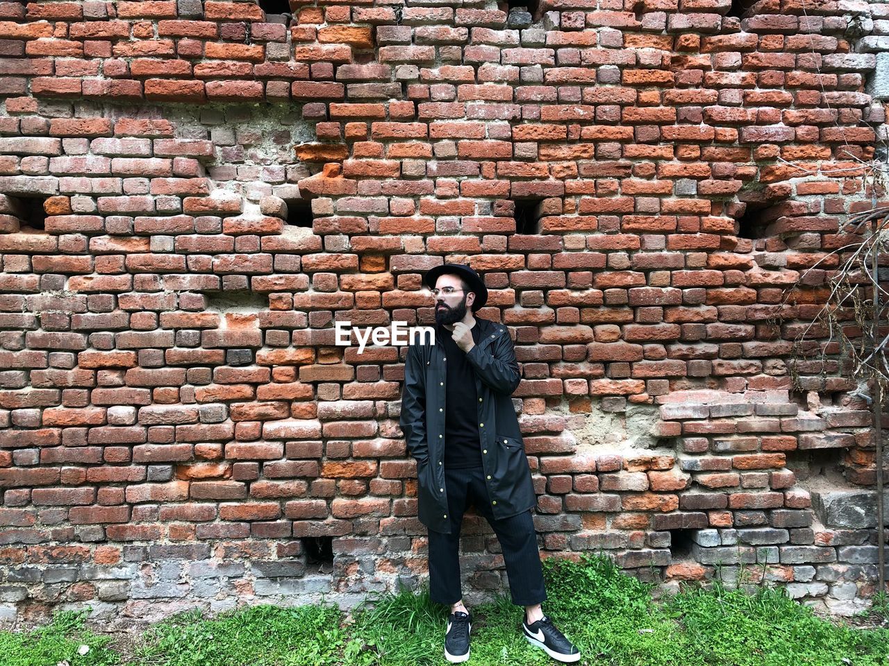 MAN STANDING AGAINST BRICK WALL