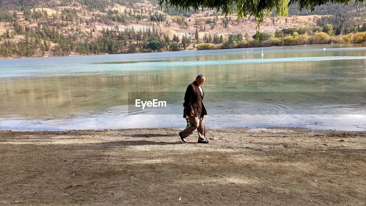 Full length of man walking by lake with grandchild