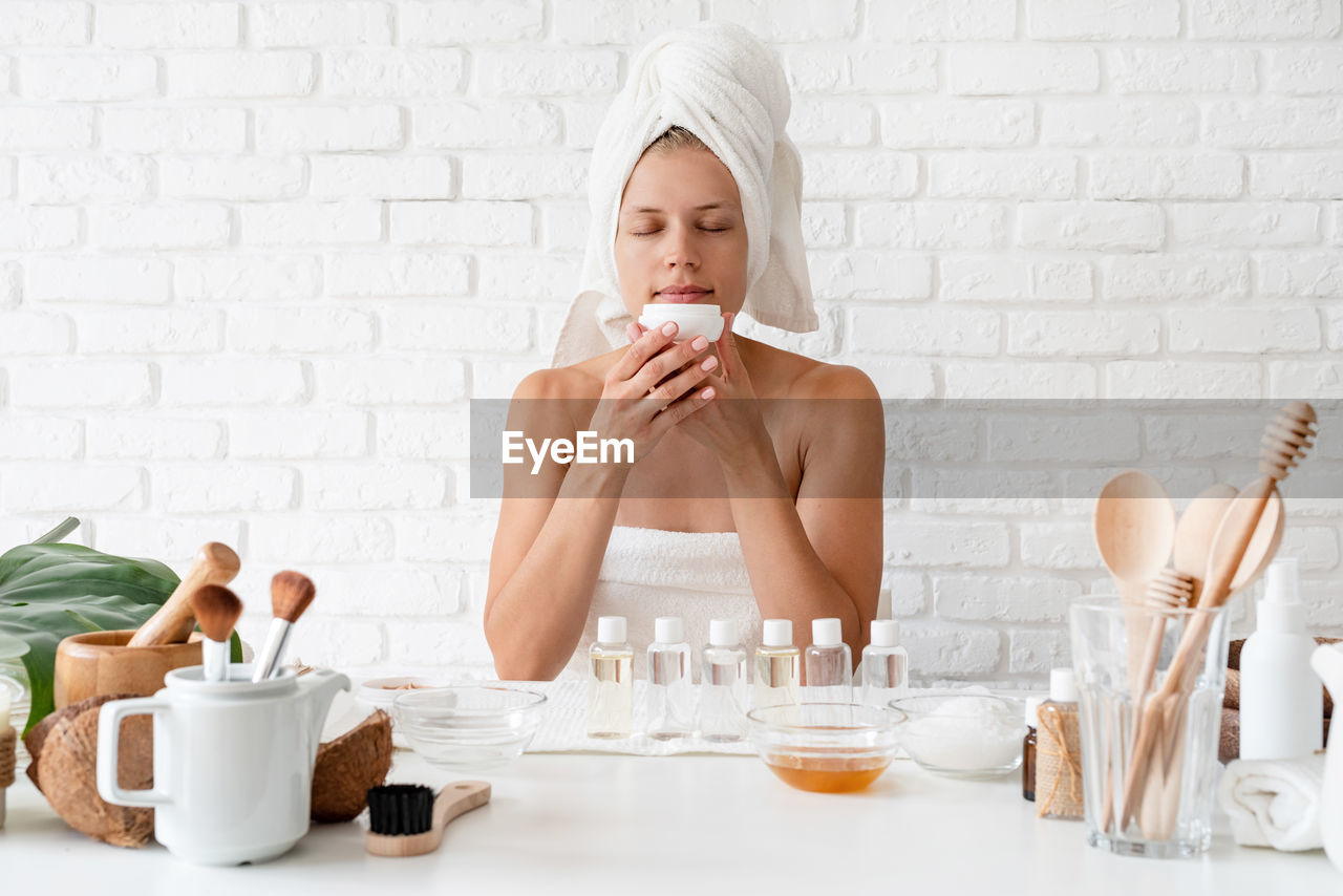 Happy young woman wear white bathrobes towels on head doing spa procedures in spa beauty salon