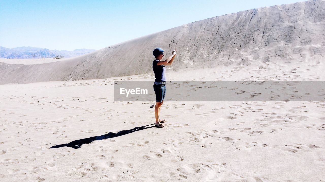 Woman photographing while standing at desert