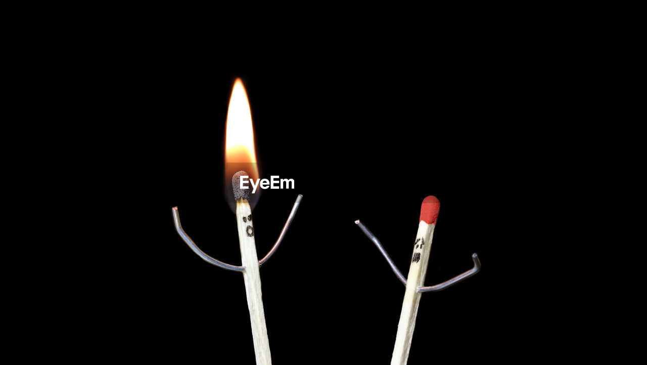 CLOSE-UP OF LIT CANDLES AGAINST BLACK BACKGROUND