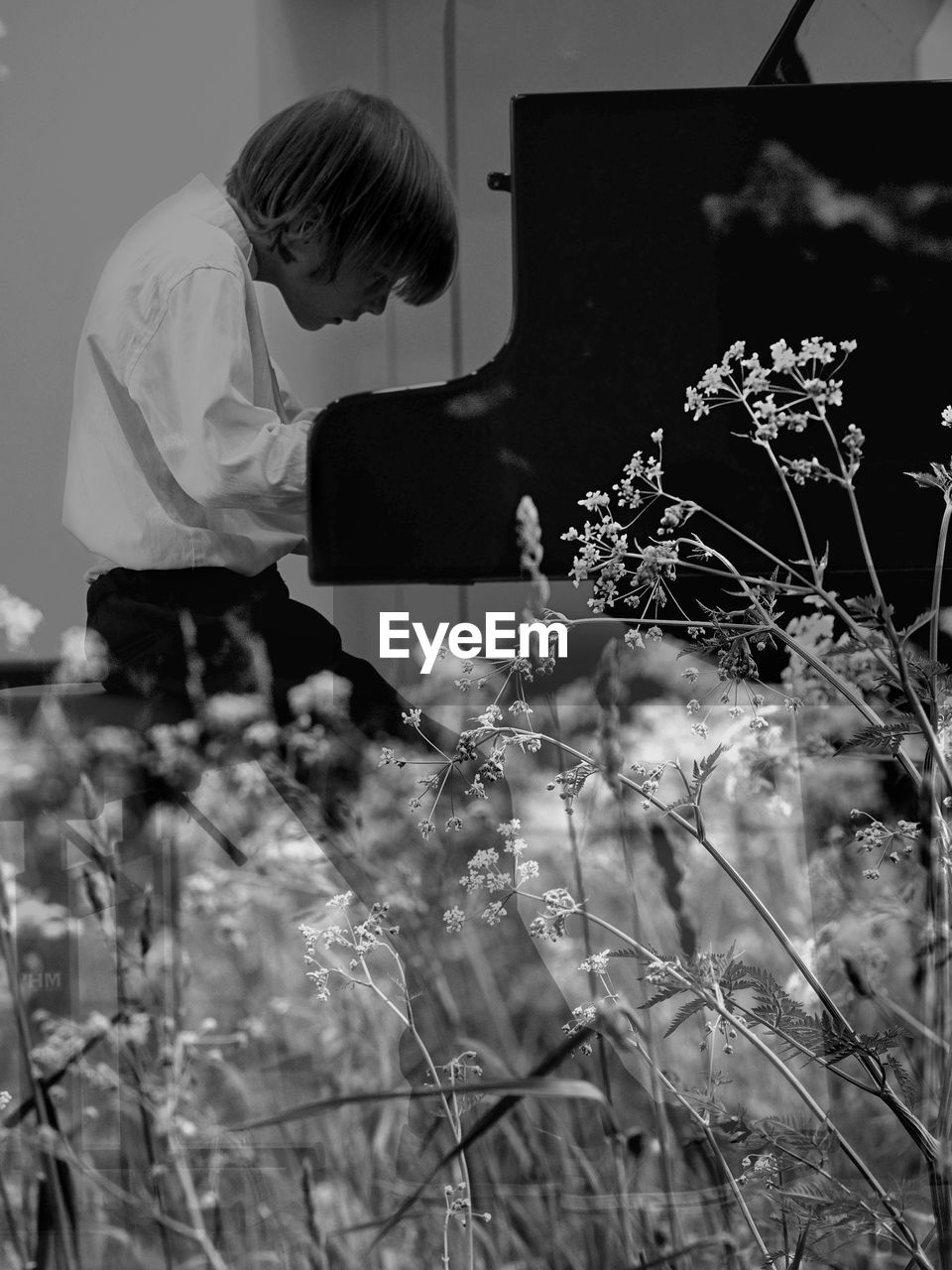 Boy playing piano while sitting by flowering plants