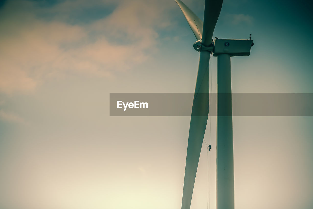 Low angle view of wind turbine against sky during sunset