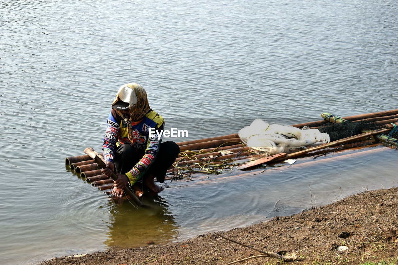 High angle view of fisherman sailing wooden raft in river