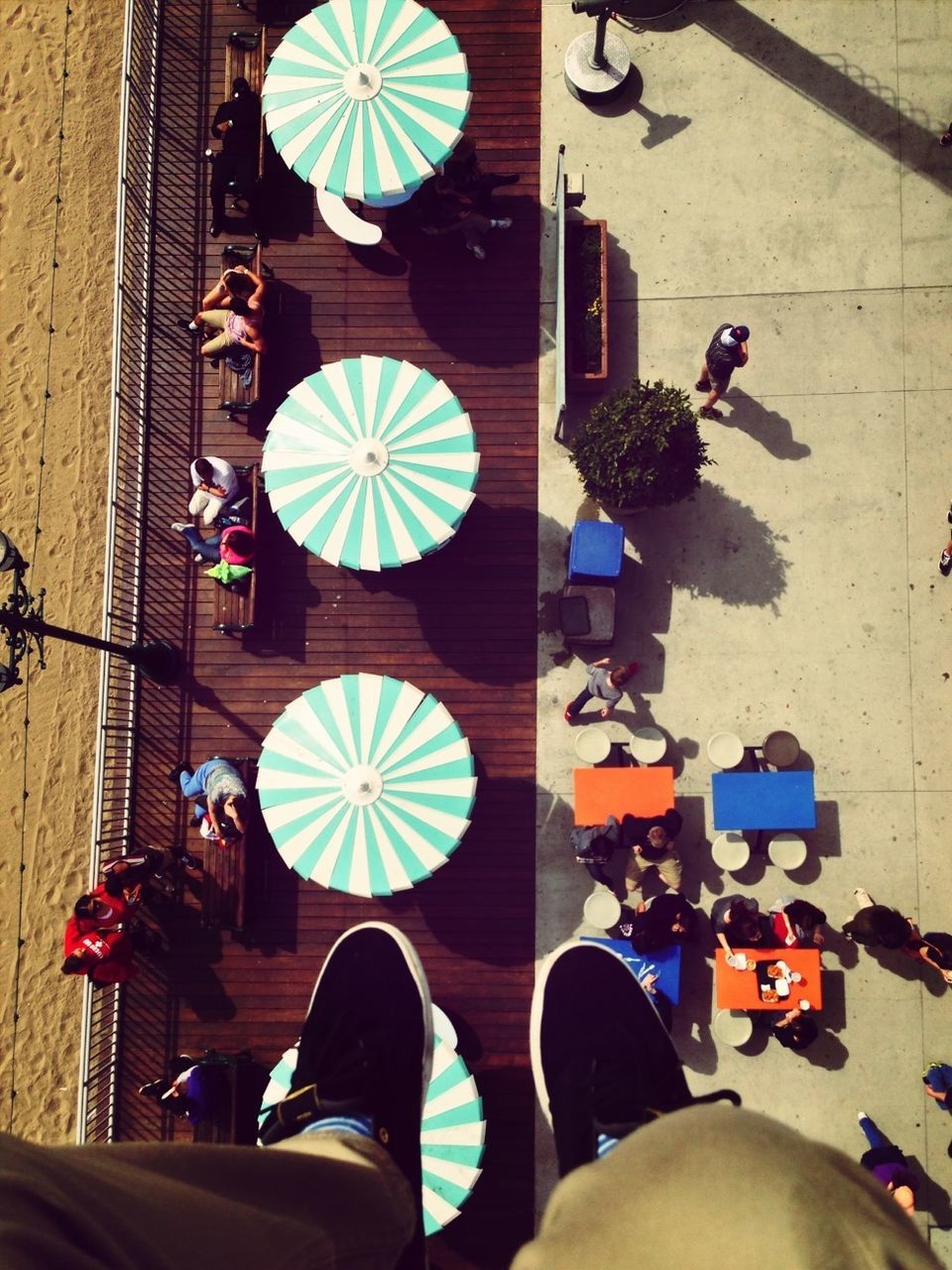 Low section of man with overhead view of people at outdoor restaurant