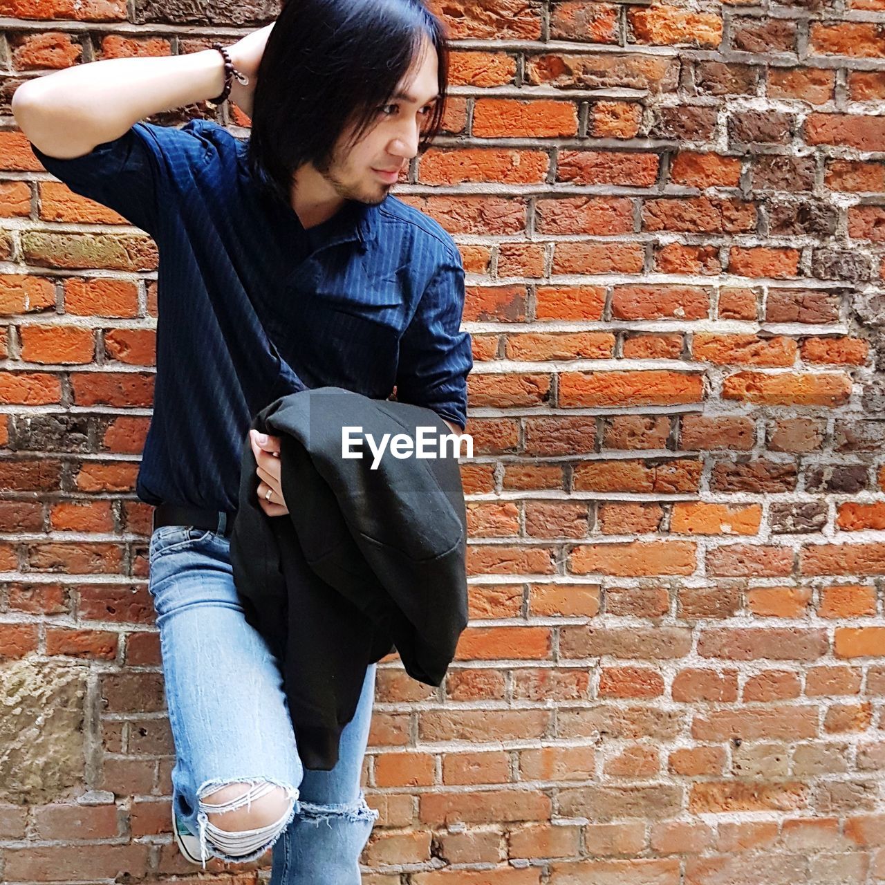 Fashionable young man posing against brick wall