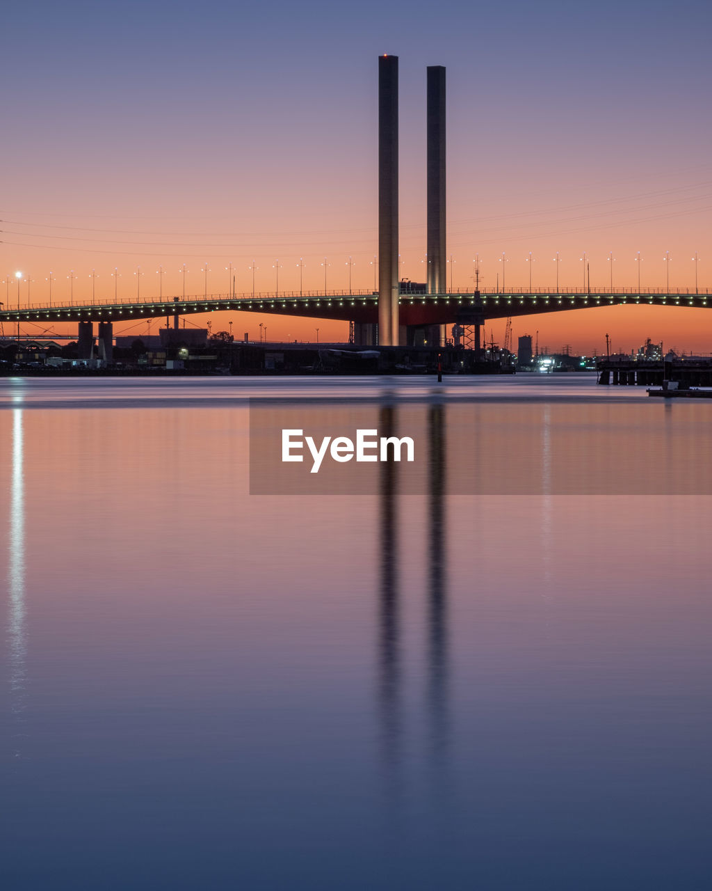 Scenic view of river by illuminated buildings against sky during sunset