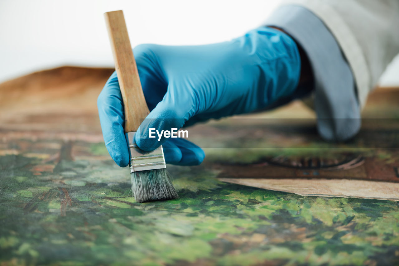 Restoring old oil painting, conservator removing varnish from an oil painting