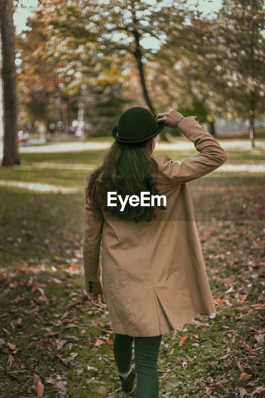 Rear view of woman walking in park during autumn