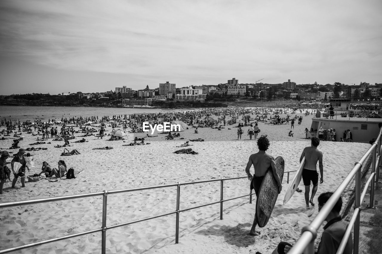 People at beach against sky in city