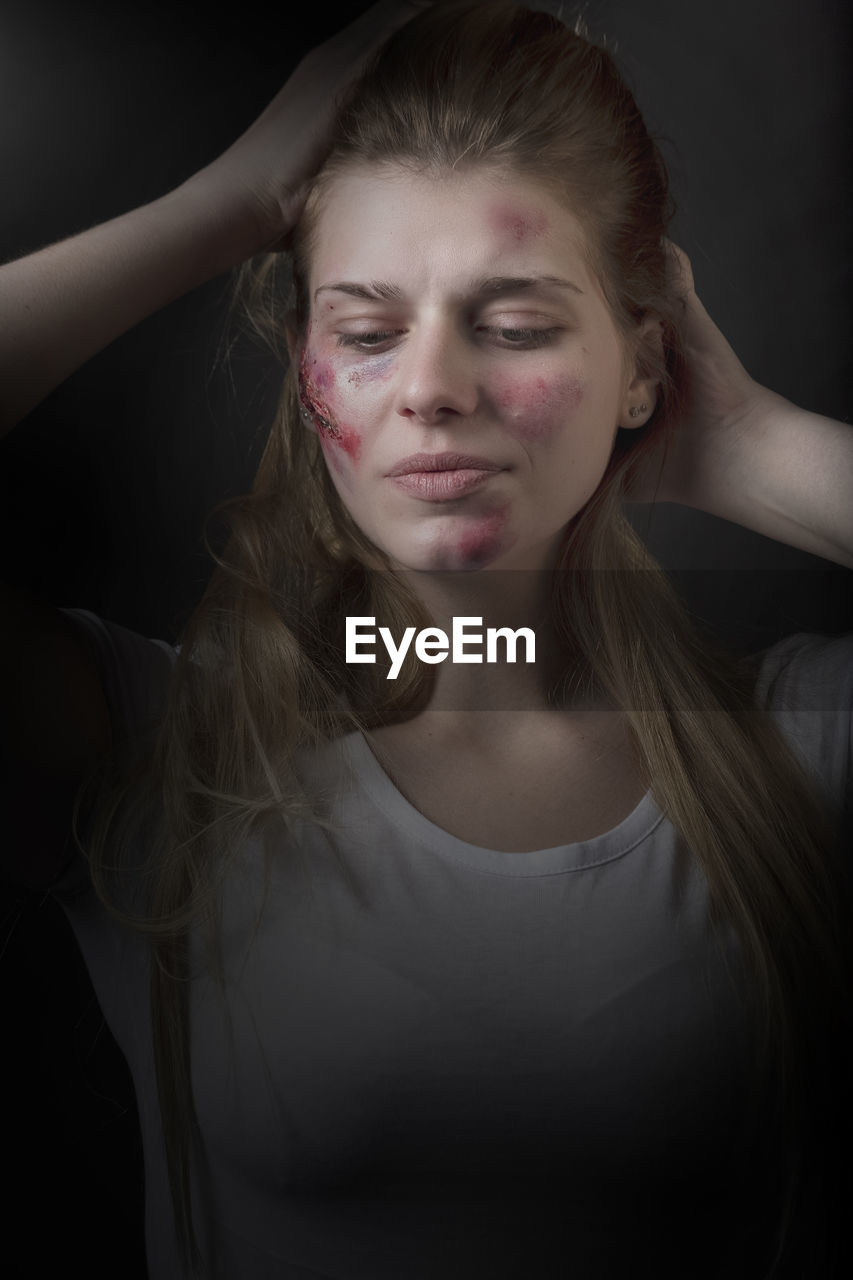 Woman with injury on face against gray background