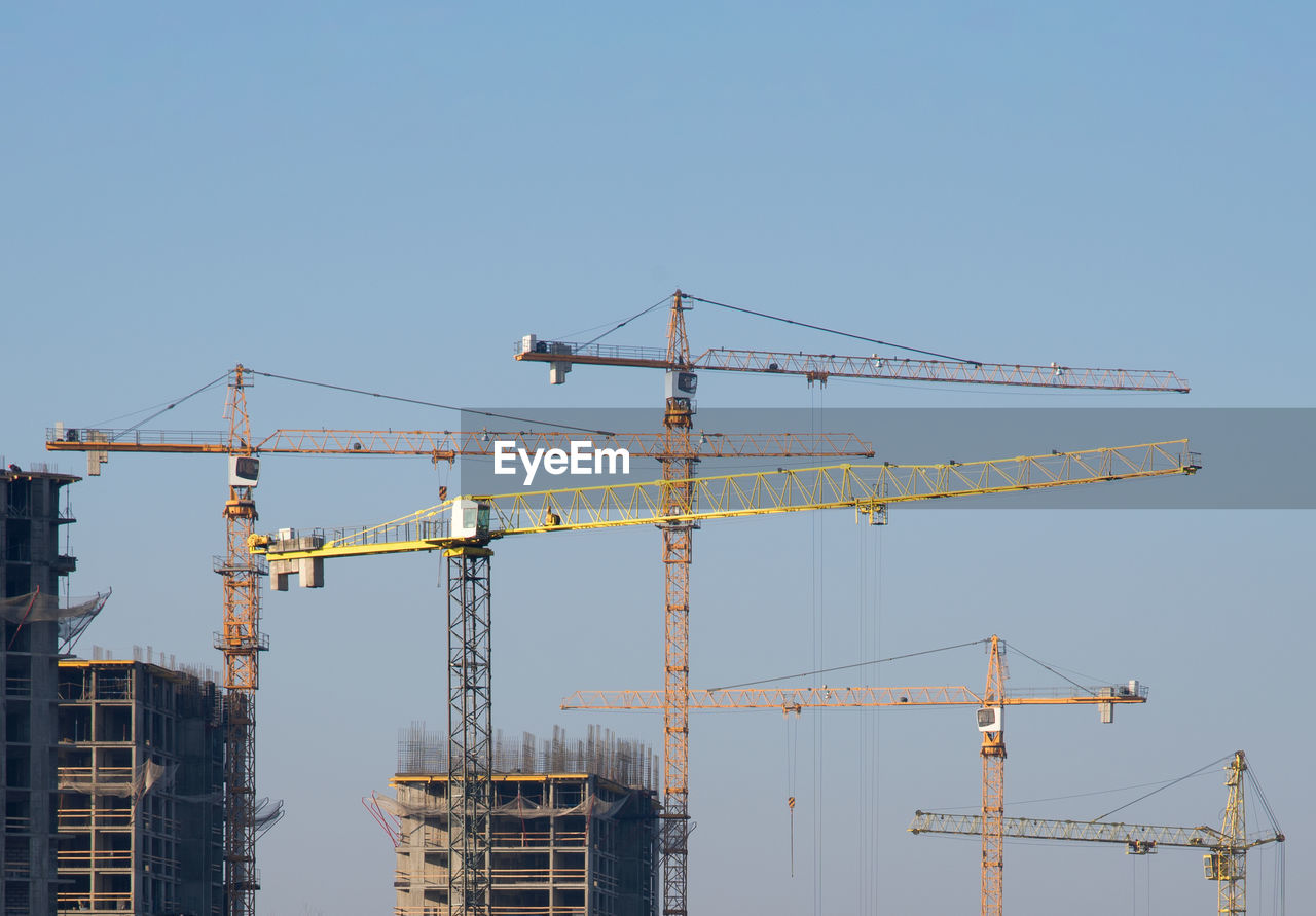 CRANE AT CONSTRUCTION SITE AGAINST CLEAR BLUE SKY