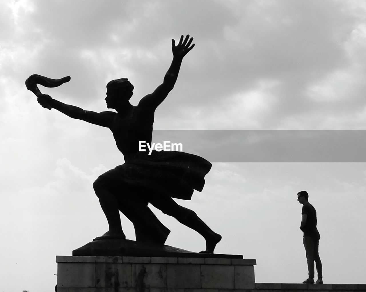 Low angle view of silhouette statues against sky