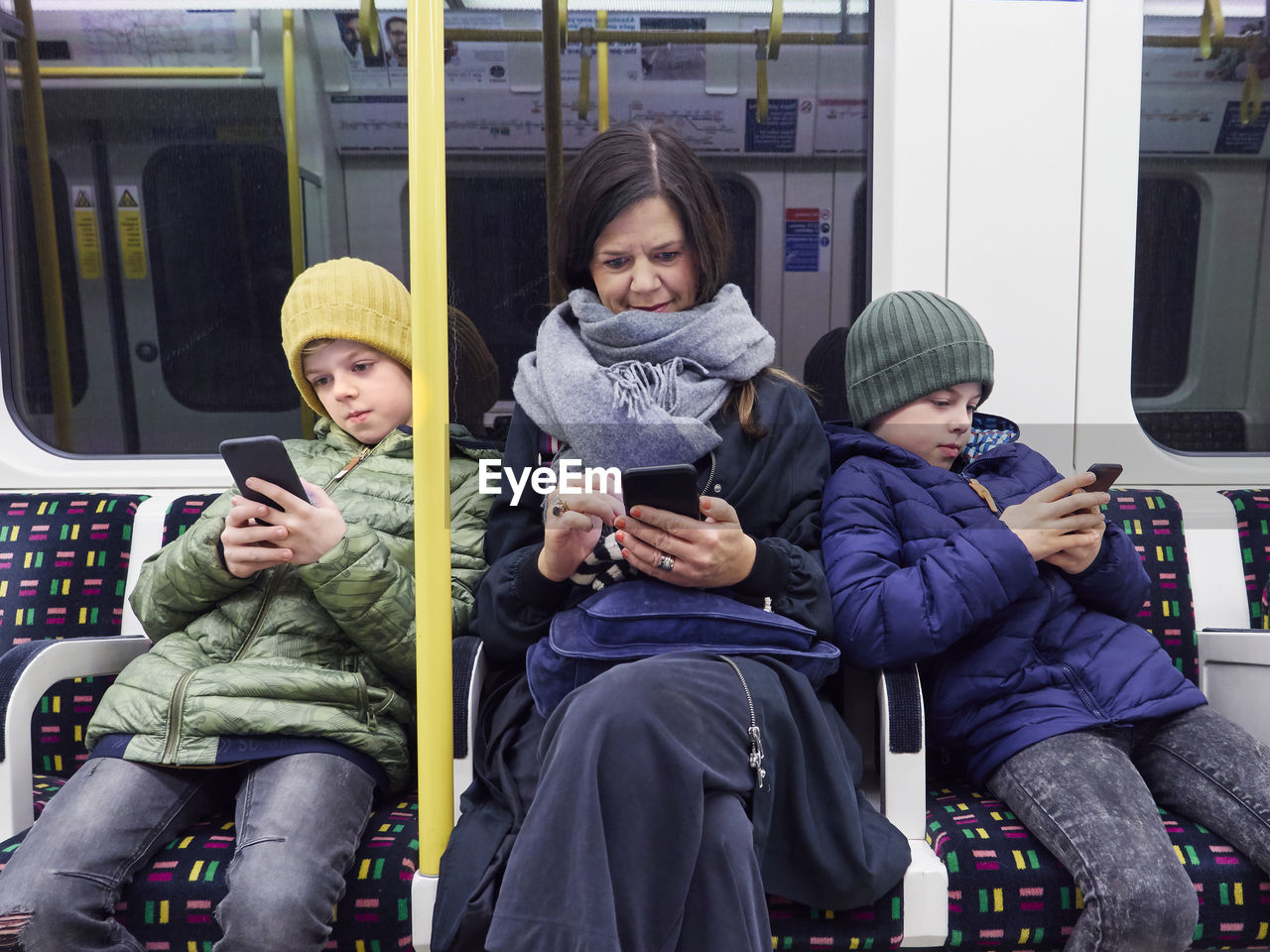 Mother and son using cell phones in subway train