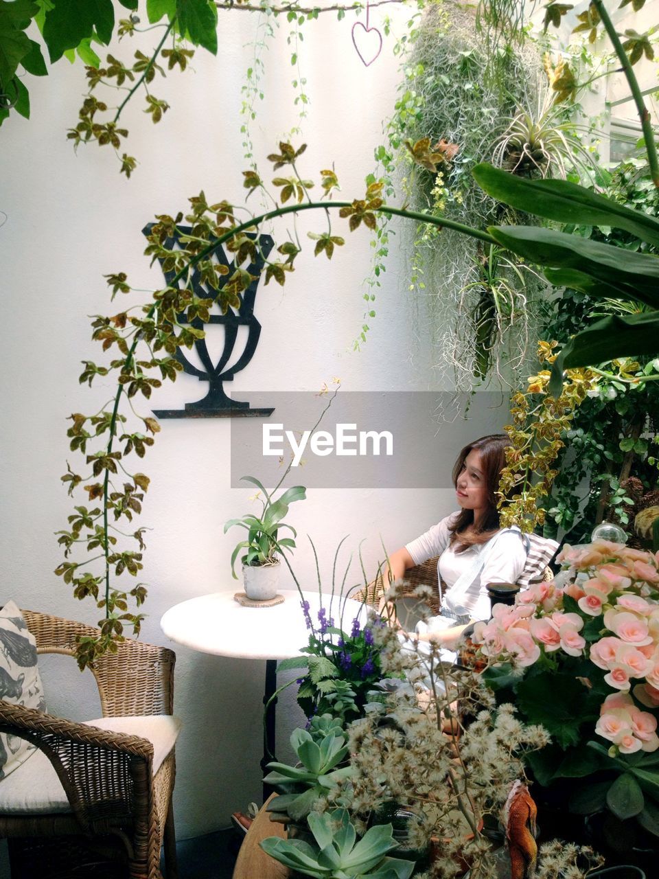 WOMAN SITTING BY POTTED PLANTS