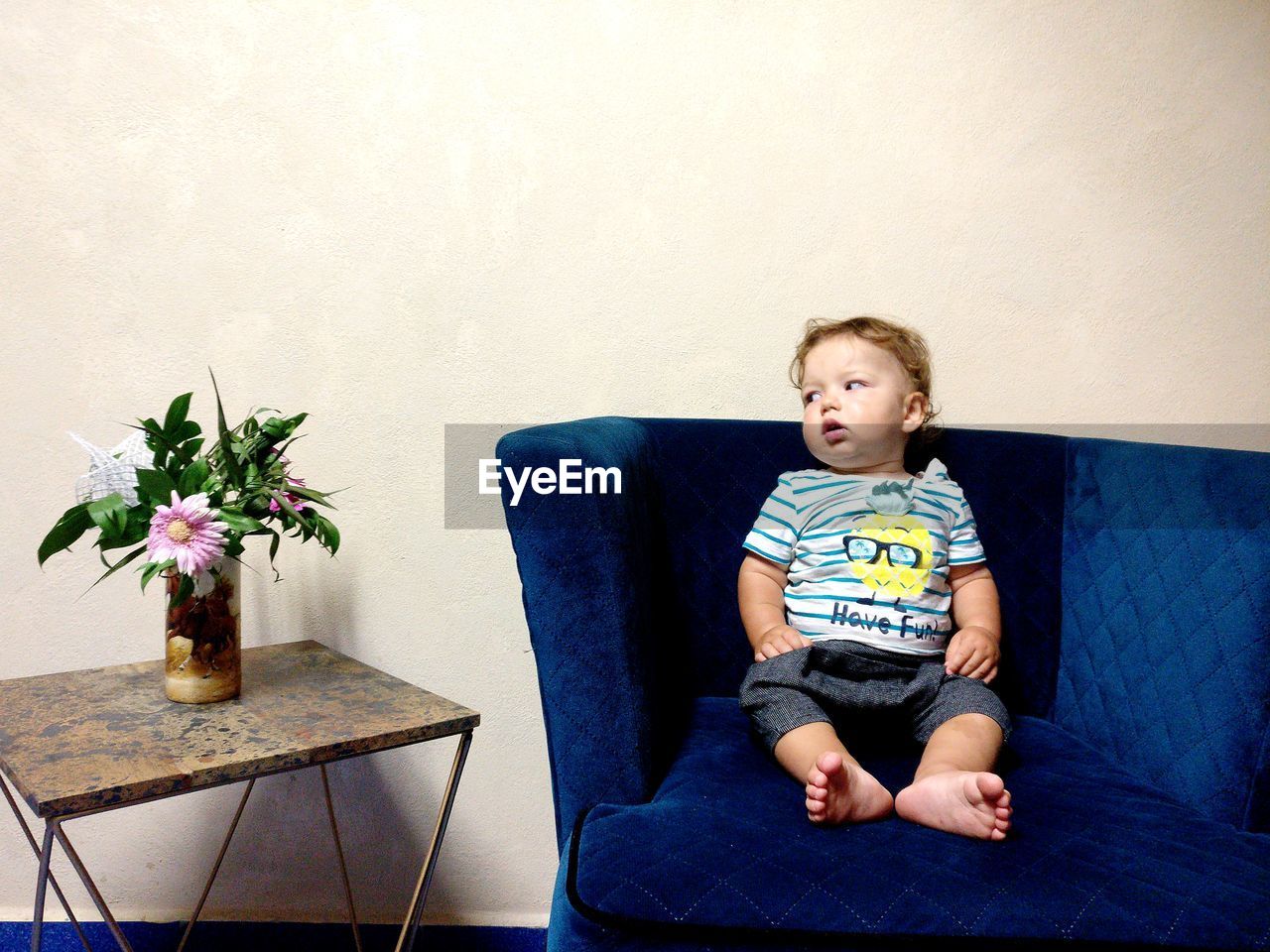 Full length of cute baby boy sitting on chair against wall at home