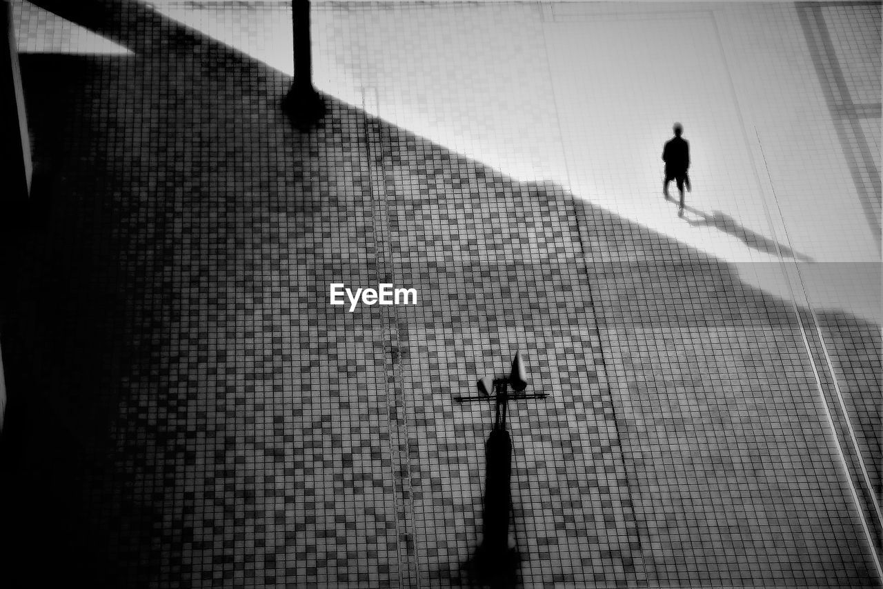 SILHOUETTE MAN AND WOMAN WALKING ON COBBLESTONE