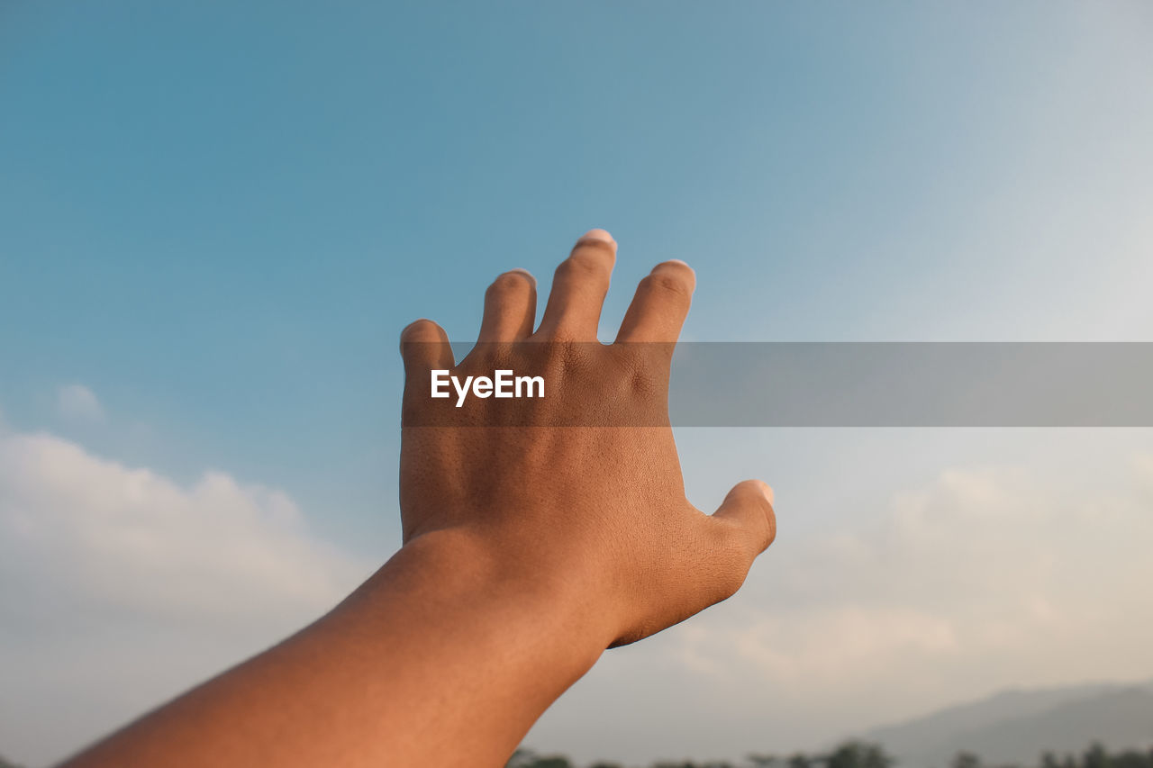 Left hand with blue sky background