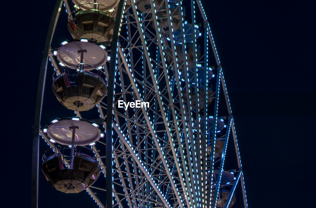 Low angle view of illuminated ferris wheel against sky at night