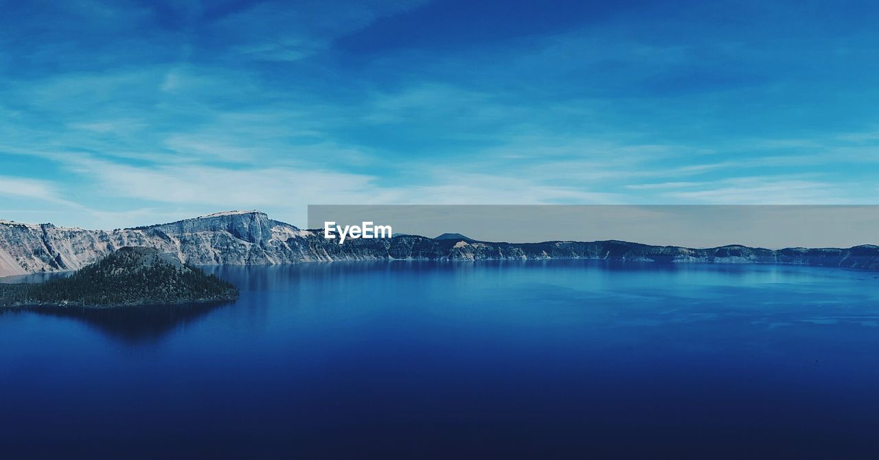 Scenic view of calm crater lake against blue sky