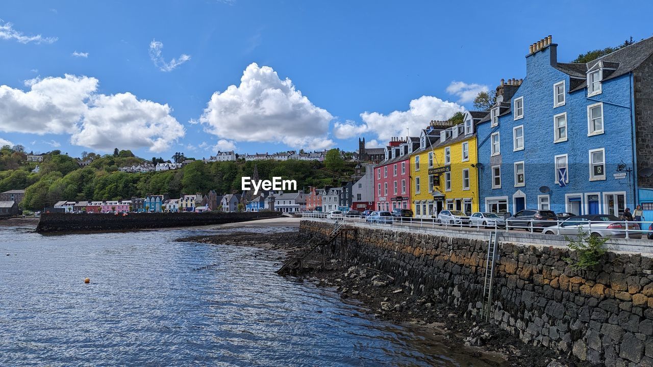 buildings by river against sky