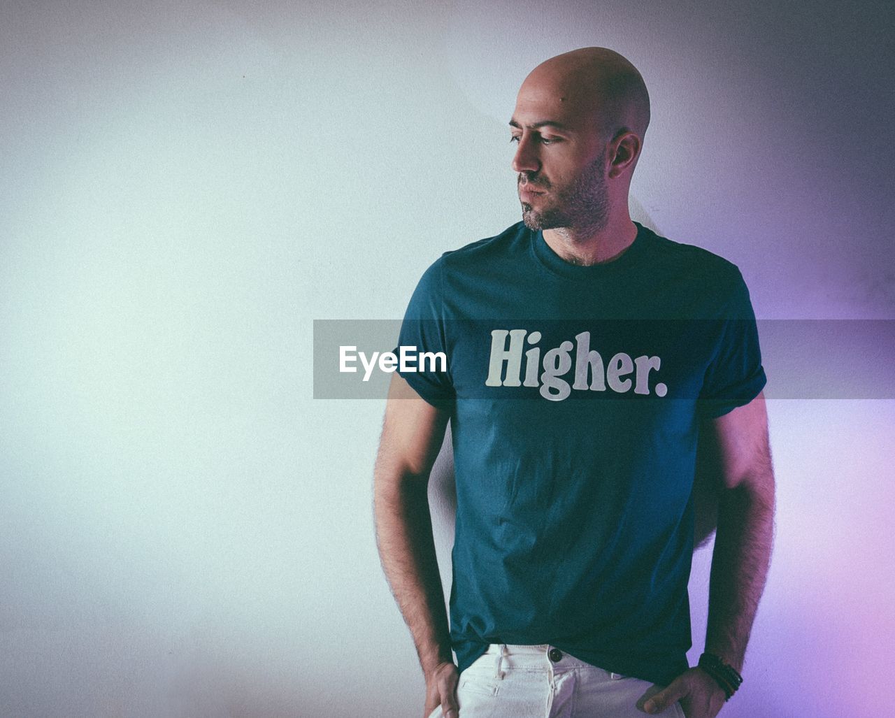 Man wearing t-shirt with text while standing against wall