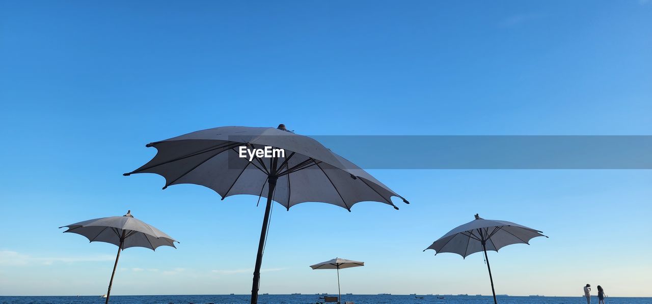 Low angle view of umbrella against clear blue sky