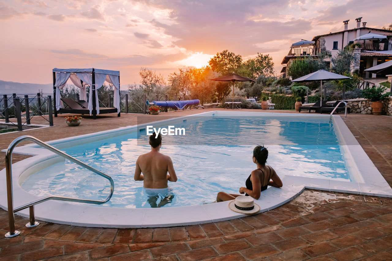 Rear view of couple in swimming pool against sky