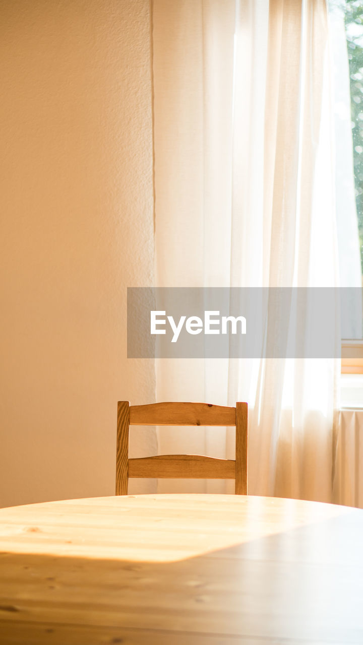 Empty chair and table against wall at home