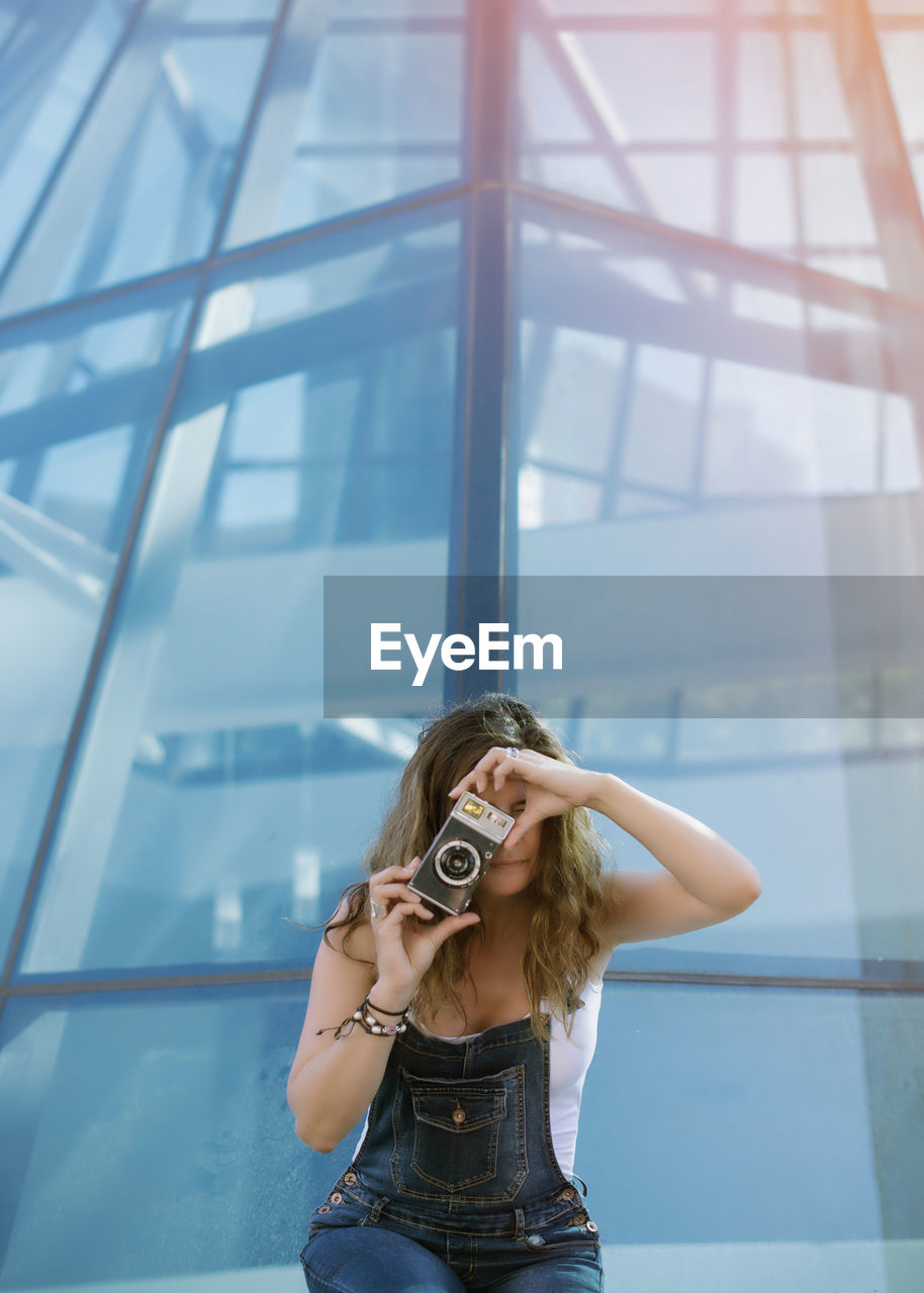 Young woman taking picture with camera in city