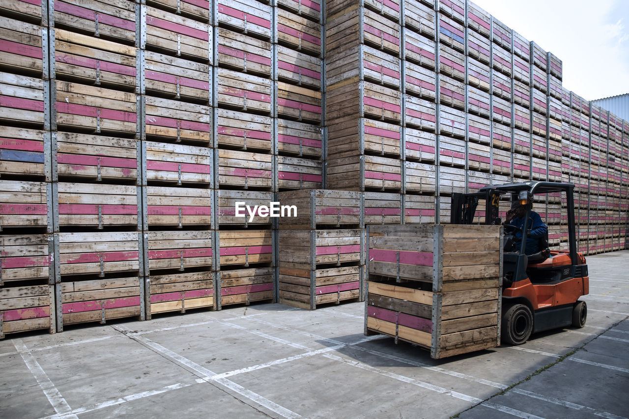 Worker on forklift moving crates on factory yard