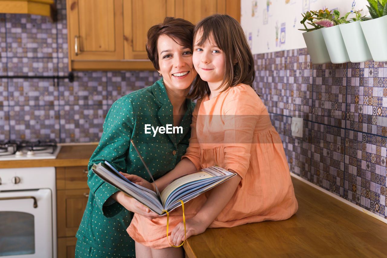 PORTRAIT OF A SMILING YOUNG WOMAN WITH BOOK